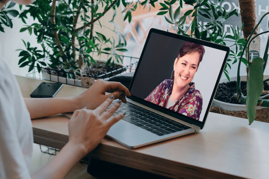 woman sitting at desk looking at laptop computer showing Rhonda Bell.