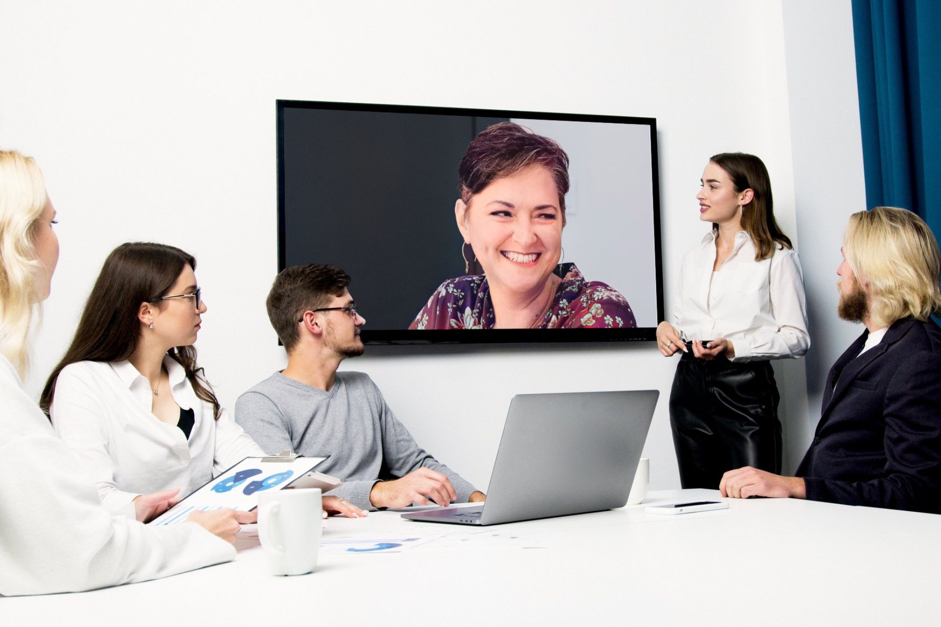 Group of people in a conference room looking at Rhonda Bell on large screen