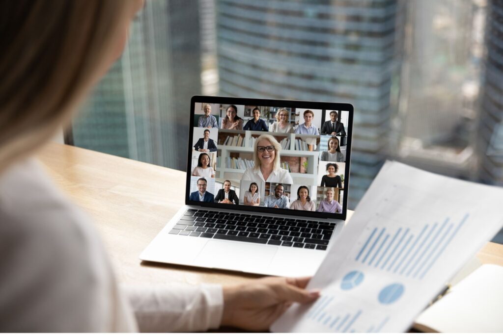 A woman looks on to a laptop computer with a group of people featured in an online session.